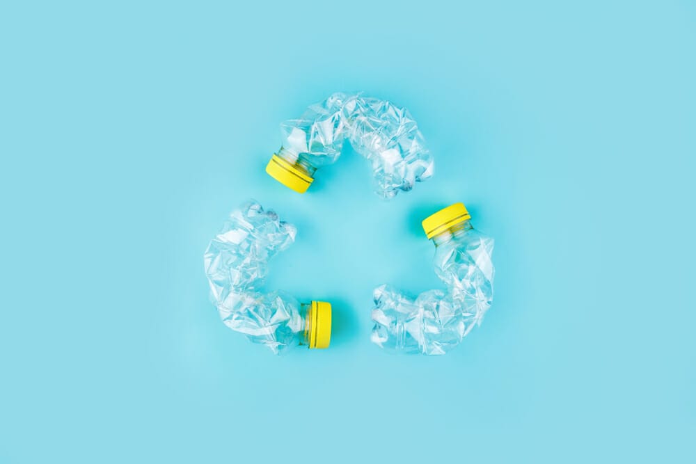 Silicone vs Plastic: Which Is Sustainable For The Environment? 2 crushed plastic bottles that form the recycling sign for a blog about silicone vs plastics